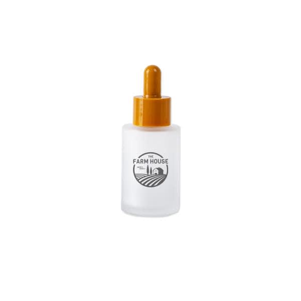 A frosted glass dropper bottle with an orange lid and a logo featuring a farm landscape. 30ml Frosted Glass Dropper Bottle - Image 1