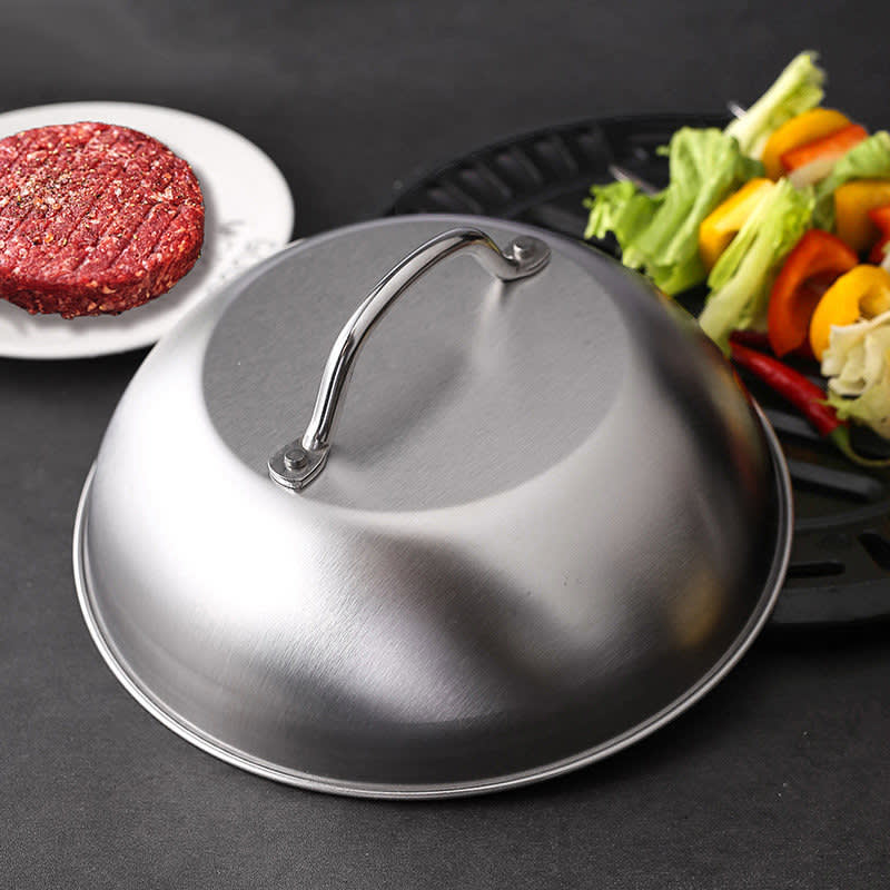 A 9-inch round stainless steel basting cover with a handle, placed next to a plate of vegetables and a burger patty. 9Inch Round Steaming Basting Cover - Image 1