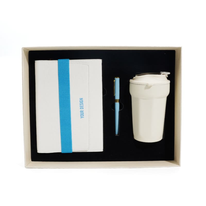A white notebook with a blue band, a blue pen, and a white cup, all presented in a gift box. Notebook And Cup Gift Box Set - Image 1