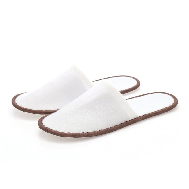 A pair of white non-slip disposable slippers with a brown sole. The slippers have a simple, unembellished design. Non-Slip Disposable Slippers - Image 1